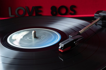 close up to a turn table needle playing a LP vinyl disc with turn table and I love 80s lettering...
