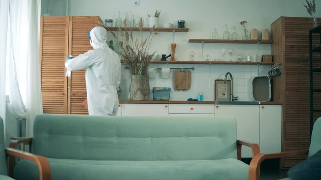 Disinfecting process during COVID-19 pandemic. Disinfector is sanitizing furniture in an apartment