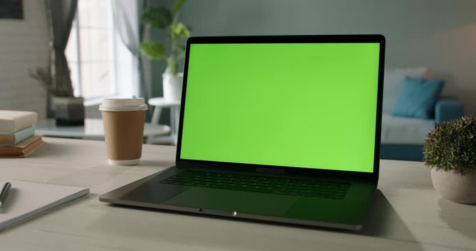 The table of distant worker at home. Modern laptop computer with chroma key green screen. Remote work, distance learning, technology concept close up 4k video template