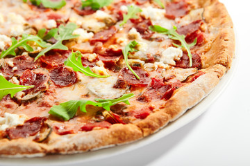 Pepperoni pizza slices with arugula on plate