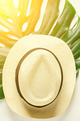 Traveler accessories. Straw hat and tropical palm monstera leaf on white background. Travel vacation, slow living, enjoying concept. Summer background. Flat lay, top view.