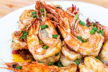 Closeup of Fried stir spicy shrimps on a white dish on wooden table. Special thai seafood. Thai Dish Cuisine. Thai food.
