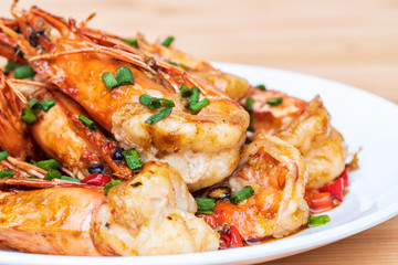 Closeup of Fried stir spicy shrimps on a white dish on wooden table. Special thai seafood. Thai Dish Cuisine. Thai food.