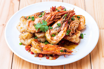 Fried stir spicy shrimps on a white dish on wooden table. Special thai seafood. Thai Dish Cuisine. Thai food.