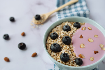 Healthy breakfast, bowl of oatmeal and yogurt with blueberries and almonds