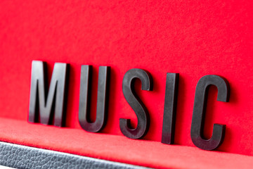 Closeup to a MUSIC black lettering word over a red background. Music lover concept