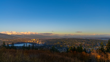 Sunset panorama over valley with sea inlet in foreground and alpine mountain on horizon
