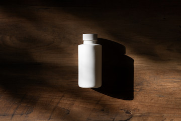 White bottle on a wooden background and shadow. Chemical Solvent Bottle with Cap