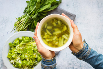 Dock sorrel green vegetables soup with potato. Russian traditional vegan food. Woman hands