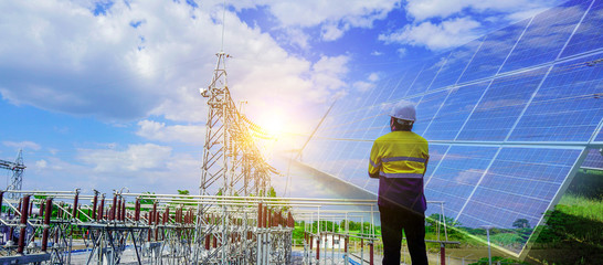 Engineer in yellow uniform, and holding a white hat, standing to look at The sunlight that makes solar cells produce clean energy. concept of alternative energy to conserve the world's energy