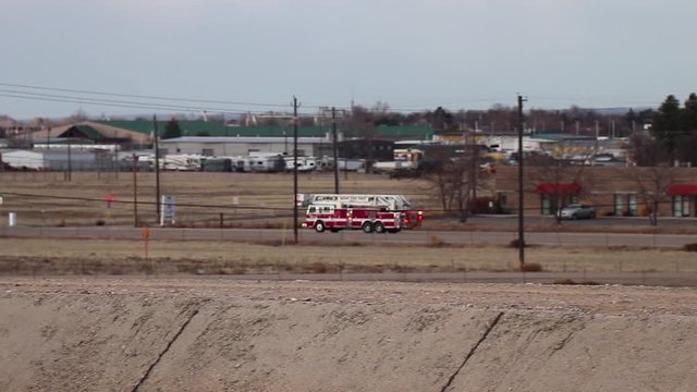 A red firetruck drives quickly down a small highway by the airport in Boise Idaho.