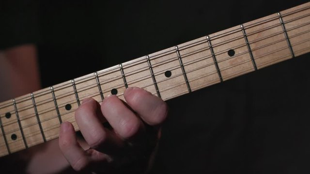 Male guitar player practices scale high up on fretboard on electric guitar, ends with chord.