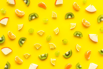 Colorful fruit pattern with citrus and kiwi slices - fresh summer fruits - on yellow background top-down