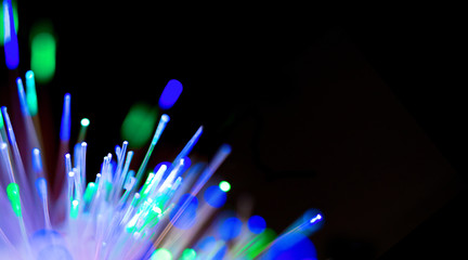 Closeup of bright multicolored luminous beams of light. Concept of of the modern technologies, big data, digital information. Technology banner with fiber optics network cable