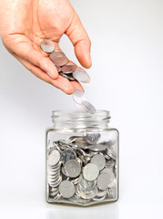 Man putting coins into jar for savings