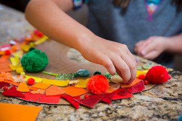 Child putting orange felt on a rainbow collage