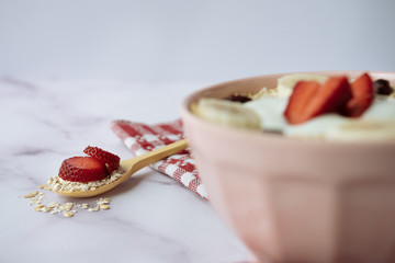 Healthy breakfast, bowl of oatmeal and yogurt with strawberry, banana and dried raisins