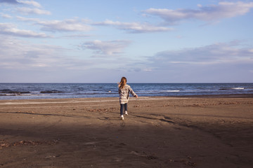 Little fashionable girl runs near the sea