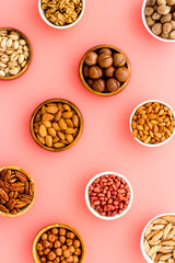 Set of macadamia, hazelnut, walnut, almond, pistachio, pecans nuts on pink background top-down pattern