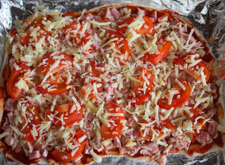 preparation for pizza with ham cheese and tomatoes