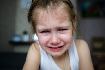little girl child cries and holds a medical protective mask