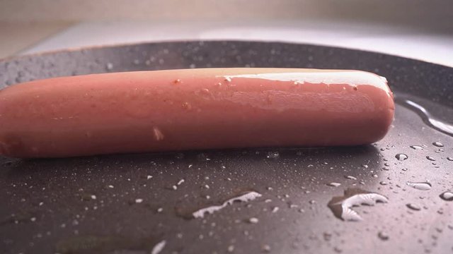 sausage falls on a hot frying pan. slow motion.