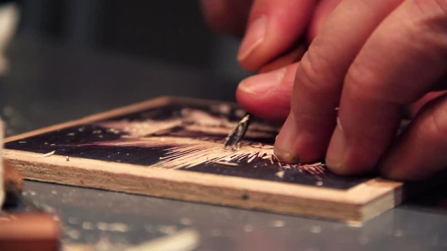Artist carves a woodblock print.
