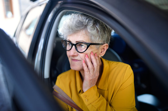 Senior Woman With Glasses Getting Out Of A Car.