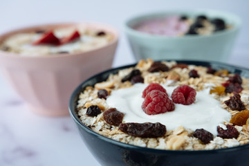Healthy breakfast, bowls of oatmeal and yogurt with raspberry, nuts, dried raisins, blueberry, strawberry, banana and almonds