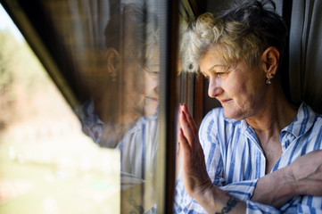 Sad senior woman standing indoors at home, corona virus and quarantine concept. - obrazy, fototapety, plakaty