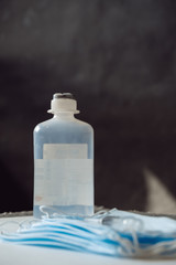 COPY SPACE: Bottle with antiseptic sanitizer and medical mask. Crisis due to coronavirus COVID-19 quarantine. Medical surgical protective face mask with antibacterial antiseptic. Copy space, template.