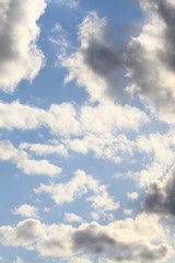 Clouds in the blue sky at sunset or dawn backlit by the sun. Place for text and design.