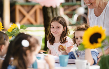 Small children eating on summer garden party, birthday celebration concept.