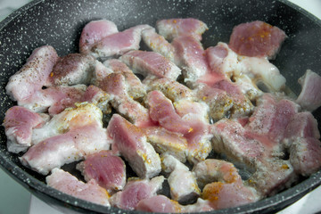 Pork fried in a black pan close-up