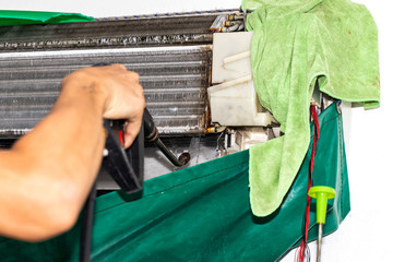 Hand holding spraying water onto are cleaning air conditioner unit. maintain and clean air...