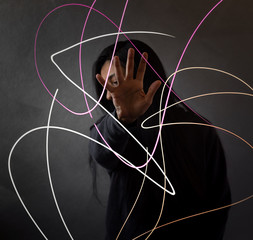 woman covering her face with her hand and lights in front of her in low exposure. Portrait 