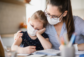 Mother and sad daughter learning indoors at home, Corona virus and quarantine concept.