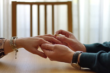 Closeup of man placing engagement ring on woman's finger