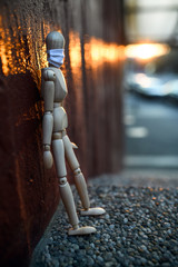 Sad and tired wooden mannequin in town, corona virus and lockdown concept.