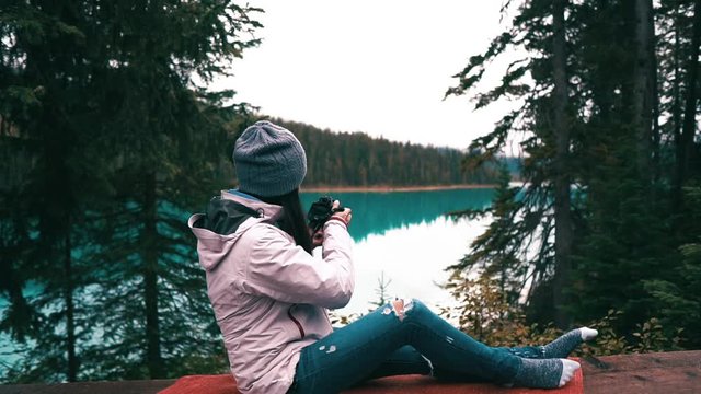 photographer girl is taking a picture of beautiful green lake in Canada