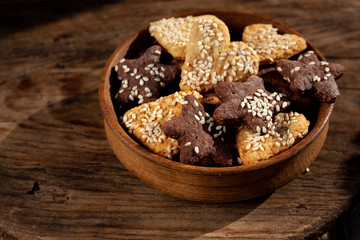 Homemade cookies with with sesame seeds in a wooden plate on a wooden background. Homemade food.