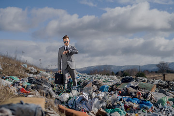 Modern businessman on landfill, consumerism versus pollution concept.