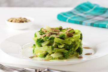 Boiled broccoli with pumpkin seeds on a white plate on the table