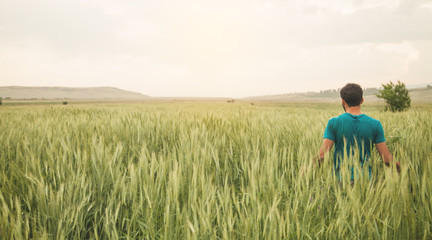 Naklejka na ściany i meble Young farmer standing in wheat field.