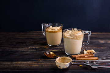 Delicious and fragrant dalgona coffee in glass cups, cinnamon sticks, dried mushrooms, a spoon of instant coffee, sugar. Cooling coffee drink with milk
