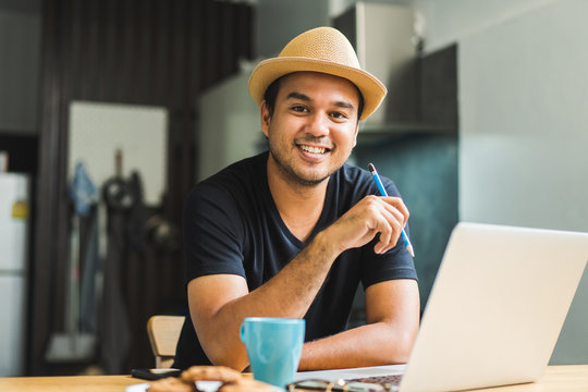 Social Distancing Concept. Asian Handsome Man Work From Home With Laptop. Young Casual Businessman Aged Around 30 Using Laptop For His Work.