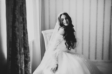 Beautiful bride wearing fashion wedding dress with feathers with luxury delight make-up and hairstyle, studio indoor photo shoot