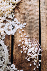 Wedding composition decorated with  pearl jewelry and invitation letter on the wooden table with lace. Jewelry closeup details from morning of the bride.