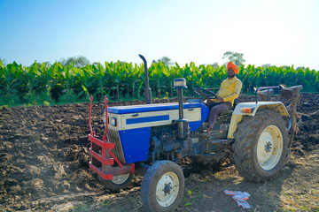 young indian farmer plowing at field