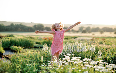 Cheerful small girl running in the backyard garden, having fun.